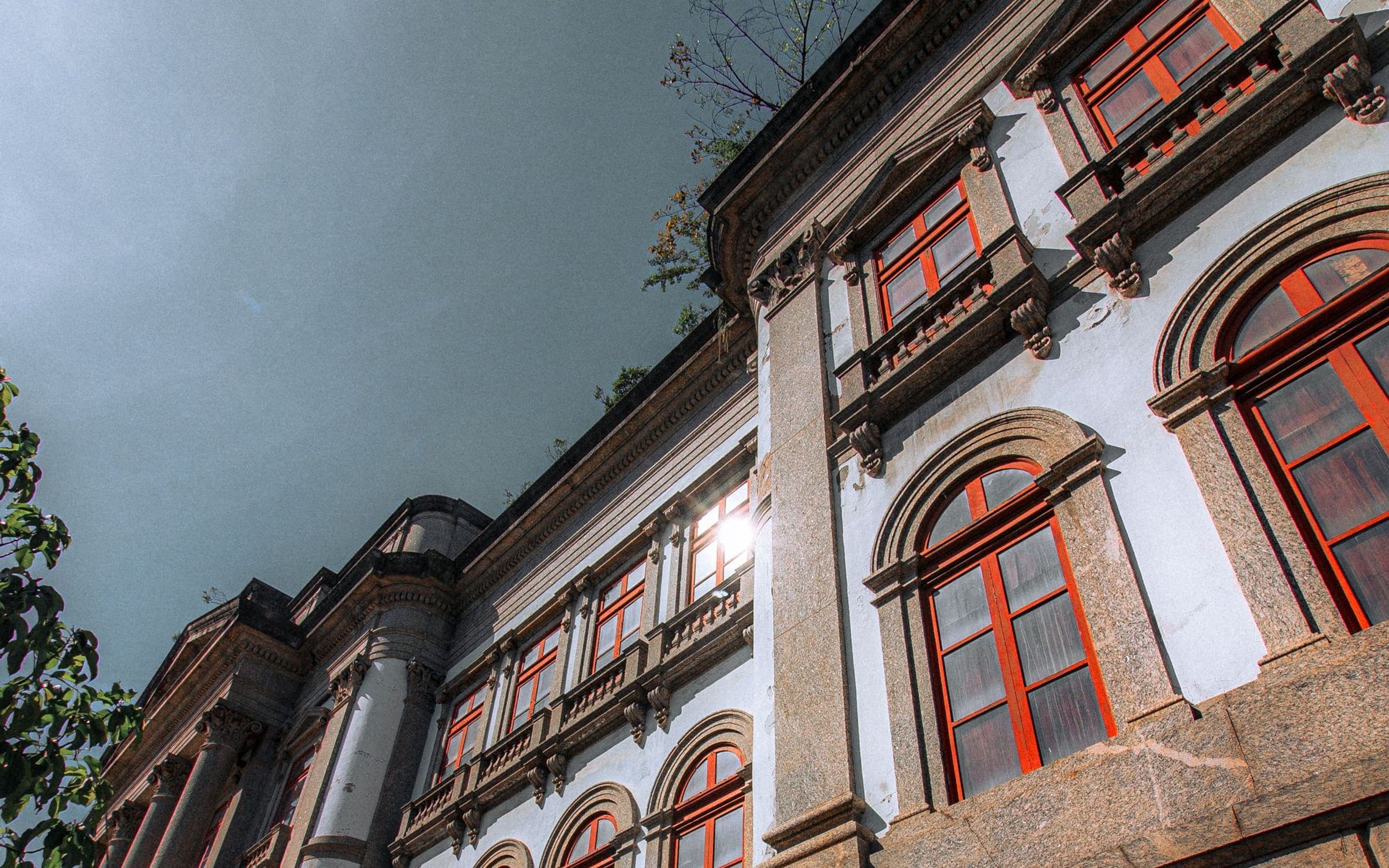 Fachada patrimonial con ventanas en arco, molduras y carpinterías de madera
